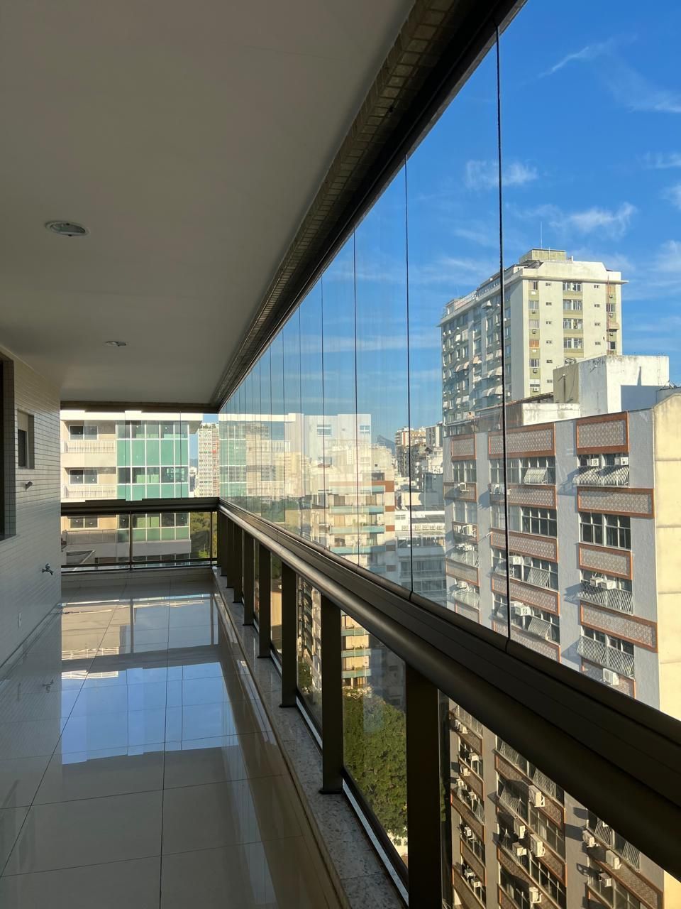 Sacada envidraçada com vista urbana e mobiliário confortável