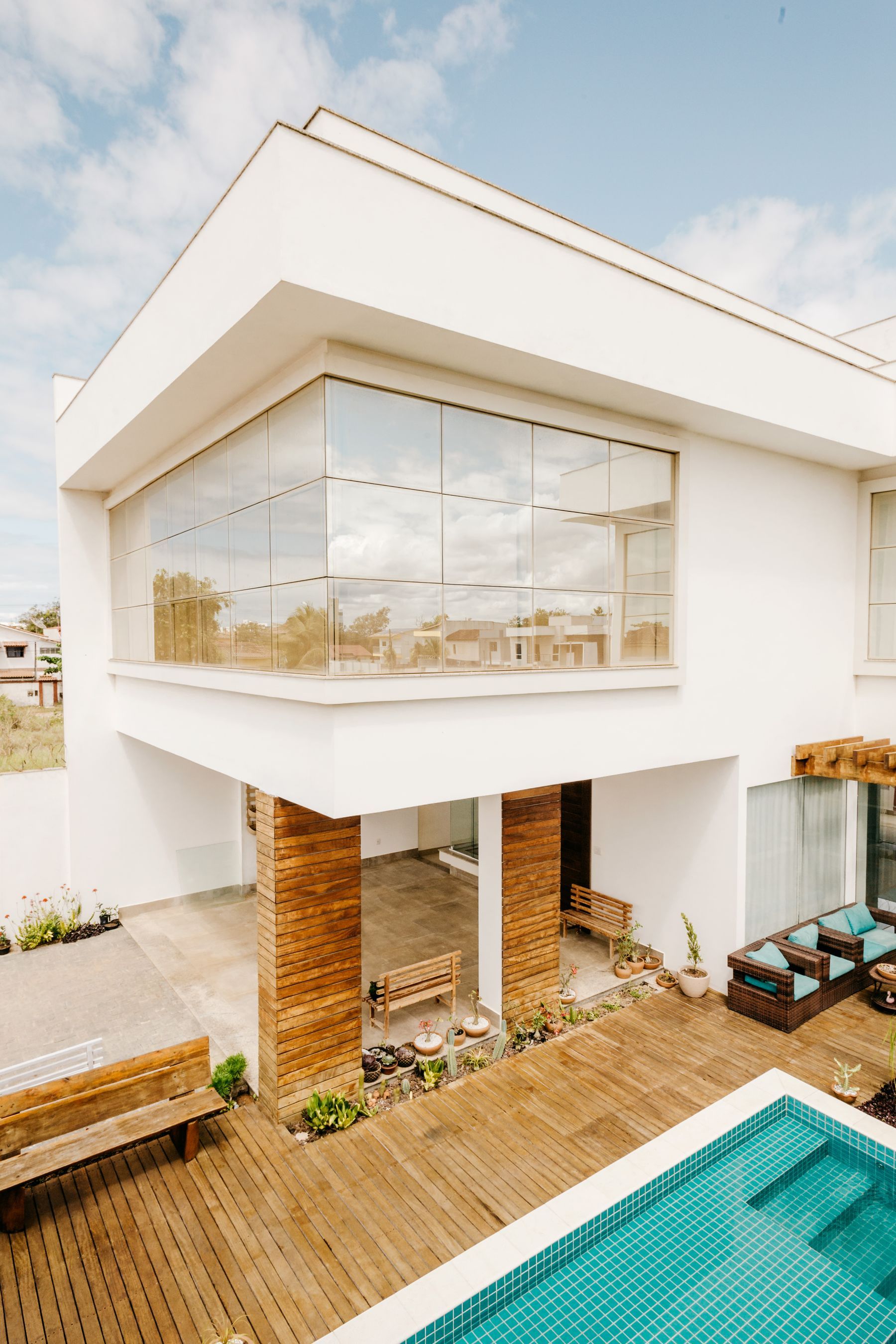 Fachada residencial formada por grandes painéis de vidro refletindo o céu